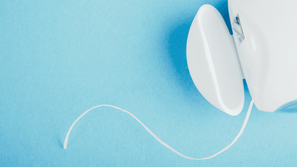 Bright white automatic electric soap dispenser on light blue background.