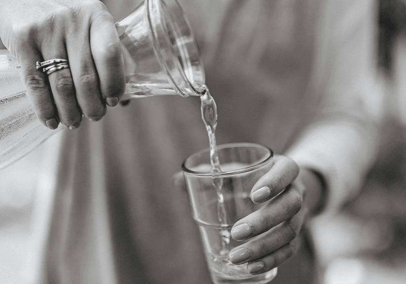 A person pouring fresh water into a glass, emphasizing hydration and wellness. Perfect for promoting healthy living and natural health remedies.